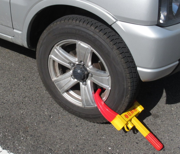 自動車の差押えにより、タイヤが特殊な錠前によりロックされ、走行が不可能な状態になっている写真